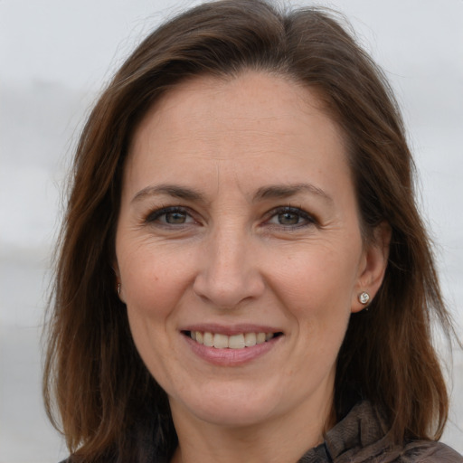 Joyful white adult female with long  brown hair and grey eyes