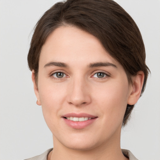 Joyful white young-adult female with short  brown hair and grey eyes