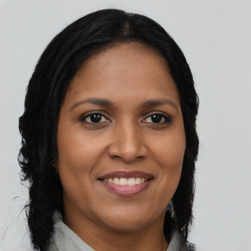 Joyful black young-adult female with long  brown hair and brown eyes