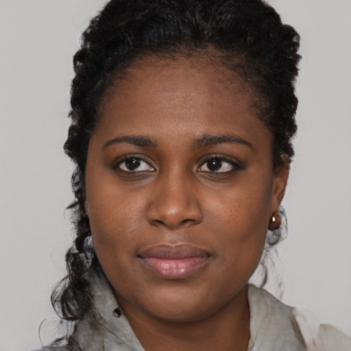 Joyful black young-adult female with long  black hair and brown eyes