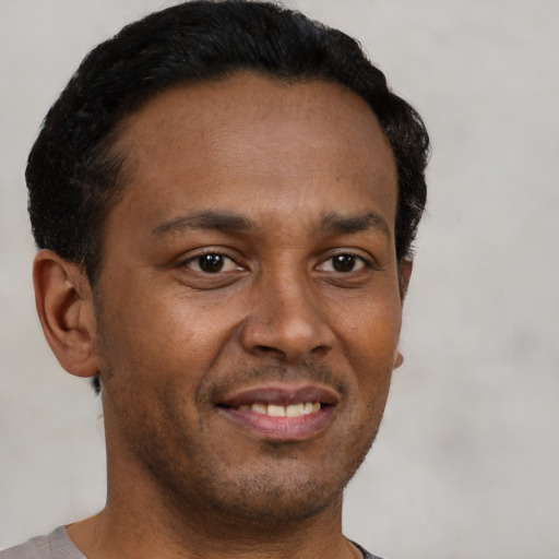 Joyful black young-adult male with short  brown hair and brown eyes