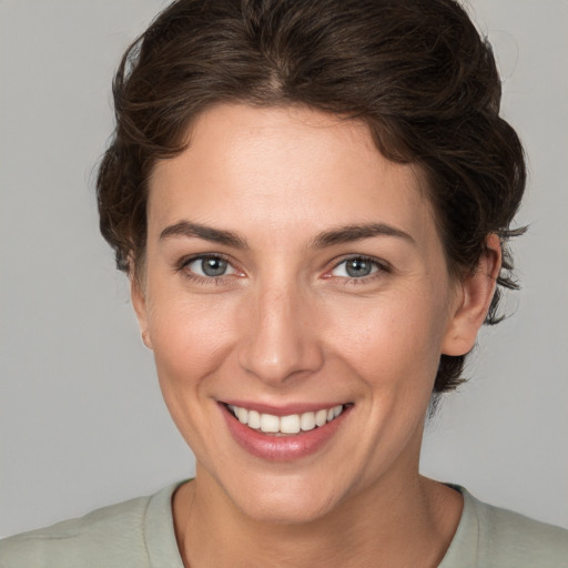 Joyful white young-adult female with short  brown hair and grey eyes