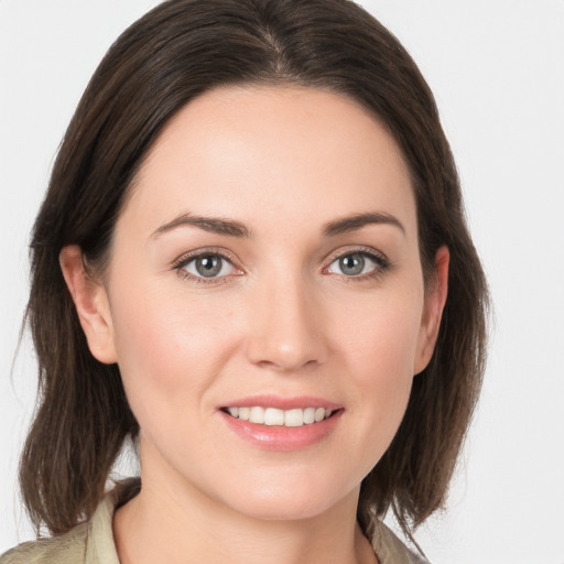 Joyful white young-adult female with medium  brown hair and grey eyes