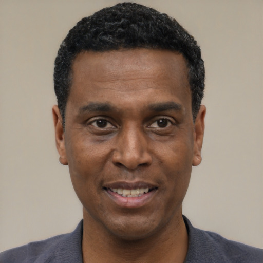 Joyful black young-adult male with short  black hair and brown eyes