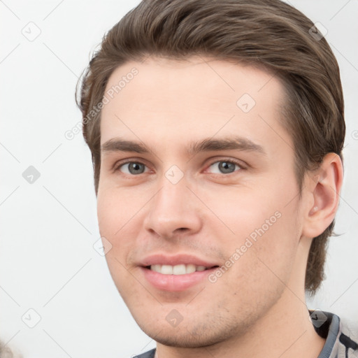 Joyful white young-adult male with short  brown hair and grey eyes