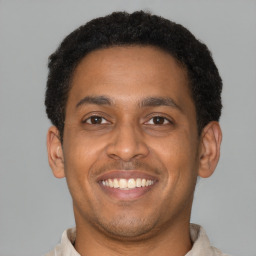 Joyful latino young-adult male with short  brown hair and brown eyes