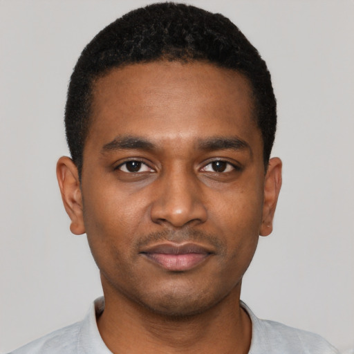 Joyful black young-adult male with short  black hair and brown eyes