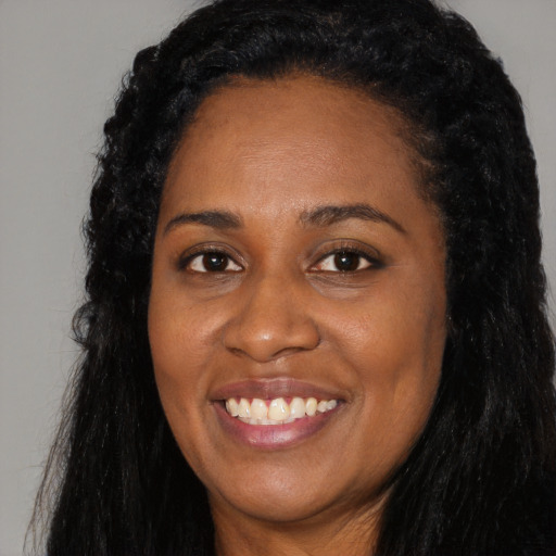 Joyful black young-adult female with long  black hair and brown eyes