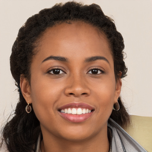 Joyful black young-adult female with long  brown hair and brown eyes