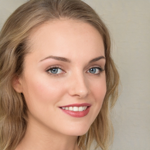 Joyful white young-adult female with long  brown hair and blue eyes