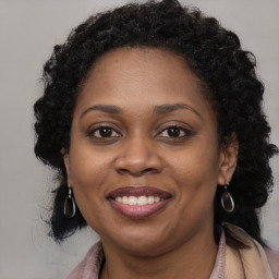 Joyful black young-adult female with long  brown hair and brown eyes