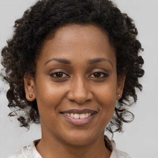 Joyful black young-adult female with medium  brown hair and brown eyes