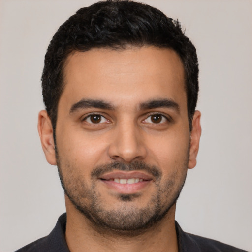 Joyful latino young-adult male with short  black hair and brown eyes