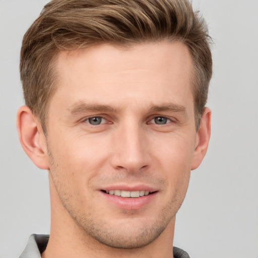 Joyful white young-adult male with short  brown hair and grey eyes