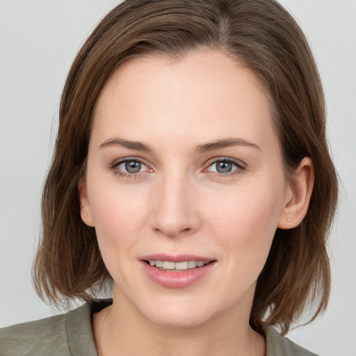 Joyful white young-adult female with medium  brown hair and grey eyes