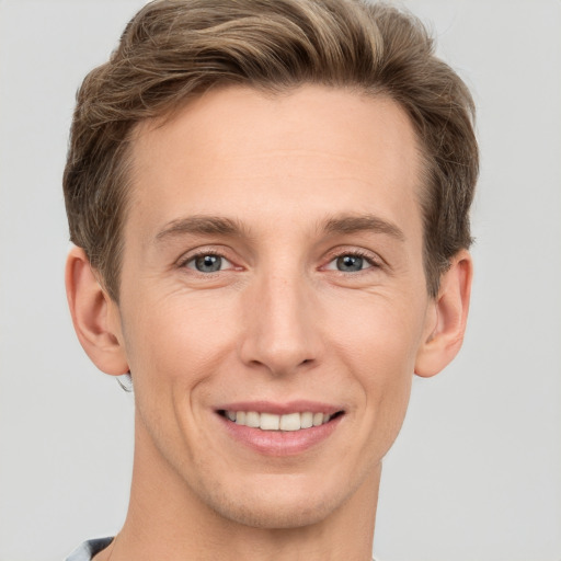 Joyful white young-adult male with short  brown hair and grey eyes