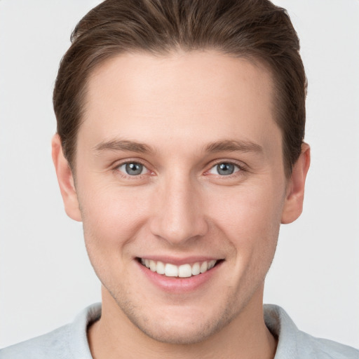 Joyful white young-adult male with short  brown hair and grey eyes