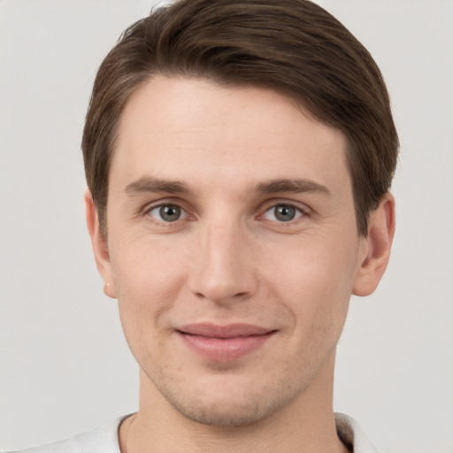 Joyful white young-adult male with short  brown hair and grey eyes