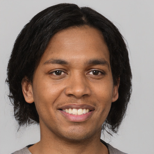 Joyful black young-adult male with medium  black hair and brown eyes