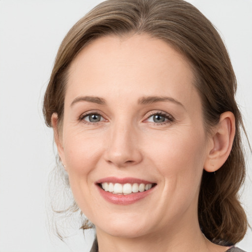 Joyful white young-adult female with medium  brown hair and grey eyes