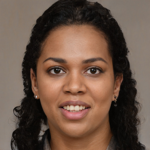 Joyful black young-adult female with long  black hair and brown eyes