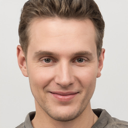 Joyful white young-adult male with short  brown hair and grey eyes