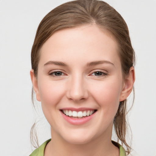 Joyful white young-adult female with medium  brown hair and green eyes