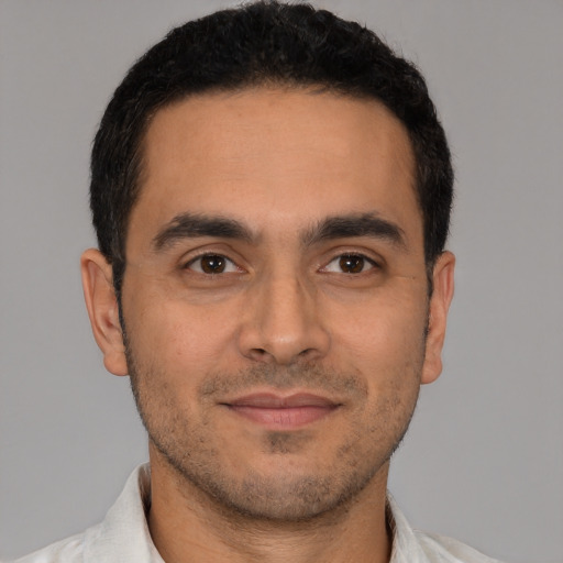 Joyful latino young-adult male with short  black hair and brown eyes