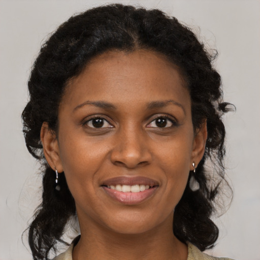 Joyful black young-adult female with long  brown hair and brown eyes