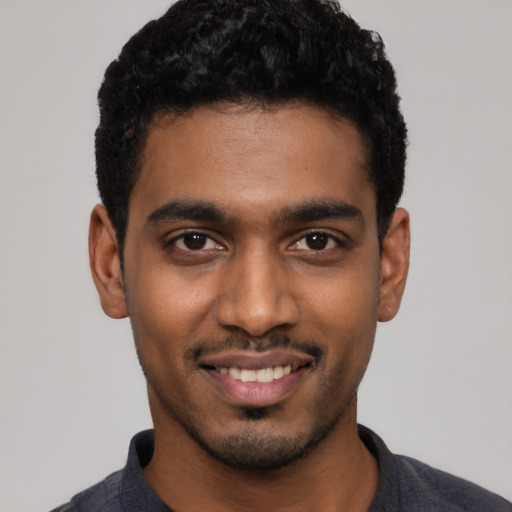 Joyful black young-adult male with short  black hair and brown eyes