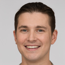 Joyful white young-adult male with short  brown hair and grey eyes