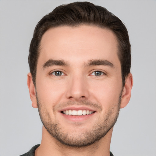 Joyful white young-adult male with short  brown hair and grey eyes