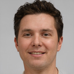 Joyful white young-adult male with short  brown hair and grey eyes