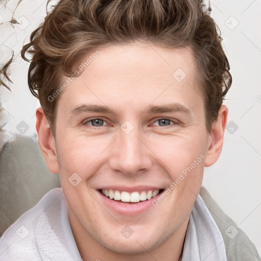 Joyful white young-adult male with short  brown hair and blue eyes