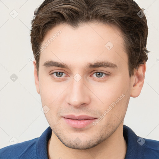 Joyful white young-adult male with short  brown hair and grey eyes