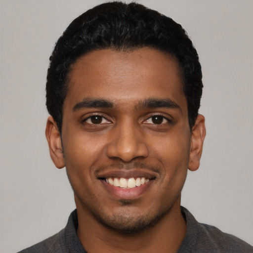 Joyful black young-adult male with short  black hair and brown eyes