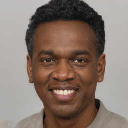 Joyful black adult male with short  black hair and brown eyes