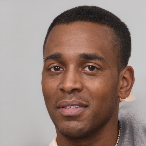 Joyful black young-adult male with short  black hair and brown eyes