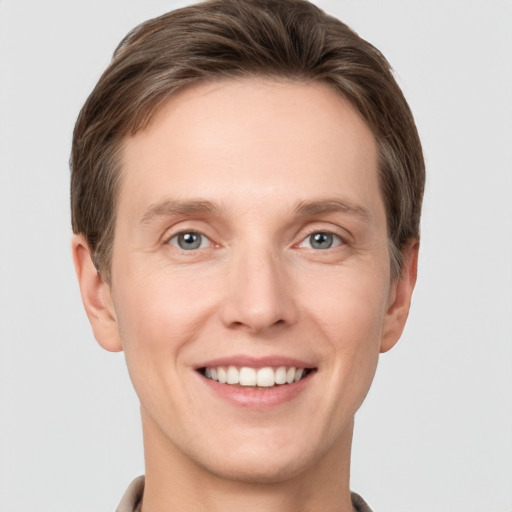 Joyful white young-adult male with short  brown hair and grey eyes