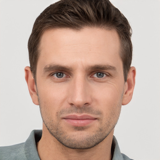 Joyful white young-adult male with short  brown hair and grey eyes