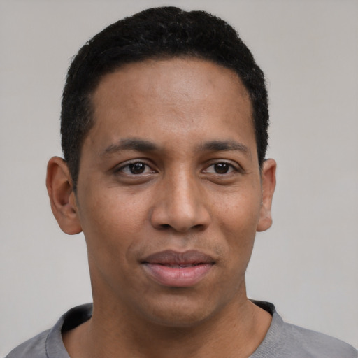 Joyful black young-adult male with short  black hair and brown eyes