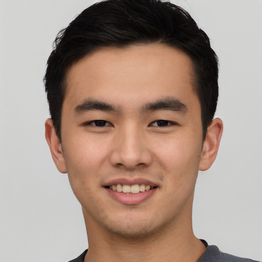 Joyful asian young-adult male with short  black hair and brown eyes