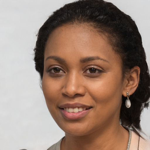 Joyful black young-adult female with long  brown hair and brown eyes