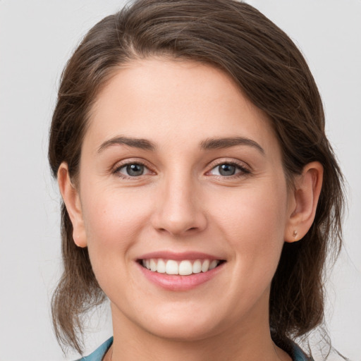 Joyful white young-adult female with medium  brown hair and grey eyes