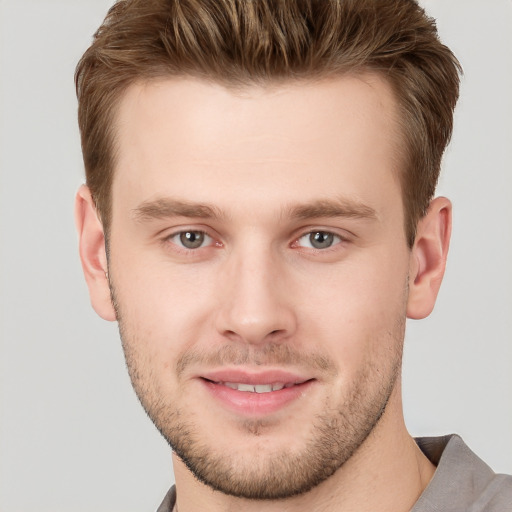 Joyful white young-adult male with short  brown hair and grey eyes