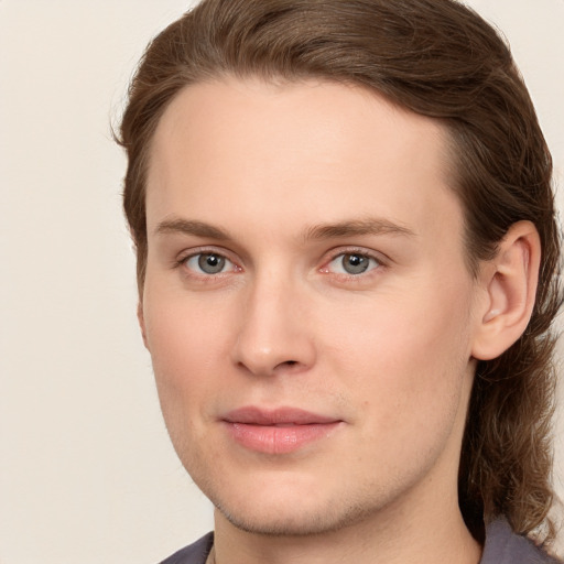 Joyful white young-adult male with long  brown hair and grey eyes