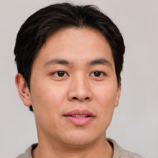 Joyful asian adult male with short  brown hair and brown eyes