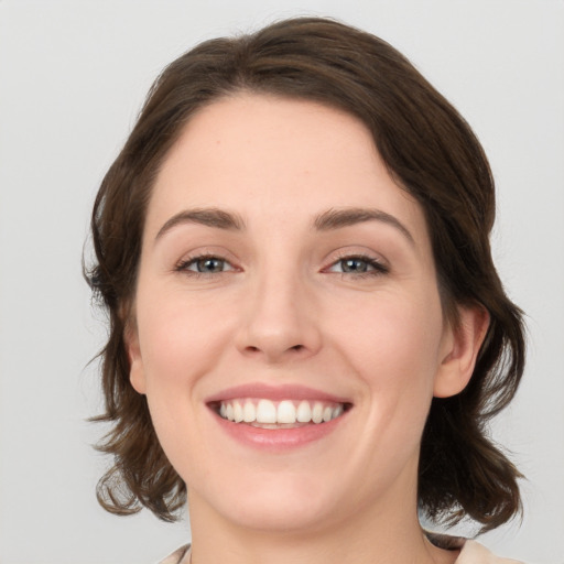 Joyful white young-adult female with medium  brown hair and green eyes