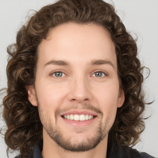 Joyful white young-adult male with medium  brown hair and green eyes