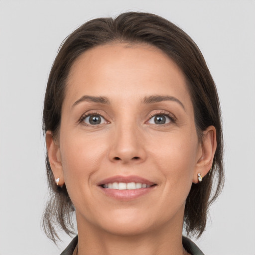 Joyful white young-adult female with medium  brown hair and grey eyes